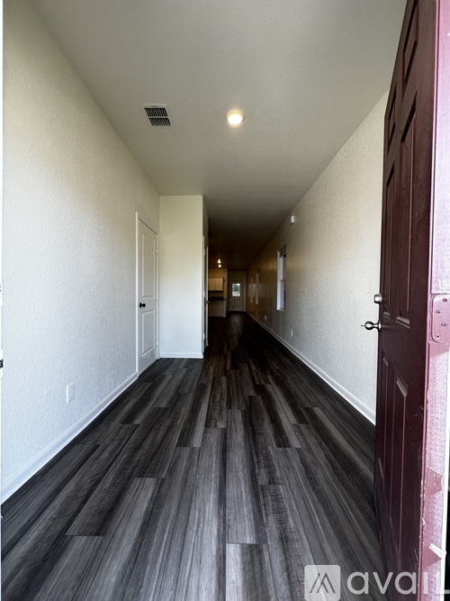 A long hallway with wood floors and white walls.