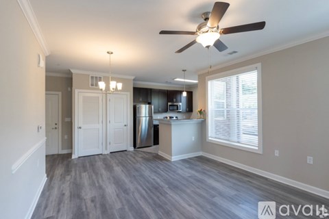 A spacious kitchen and living room with a ceiling fan and lighting fixtures.