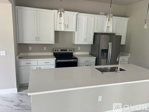 A kitchen with white cabinets and a stainless steel refrigerator.