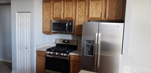A kitchen with a stainless steel refrigerator and wooden cabinets.