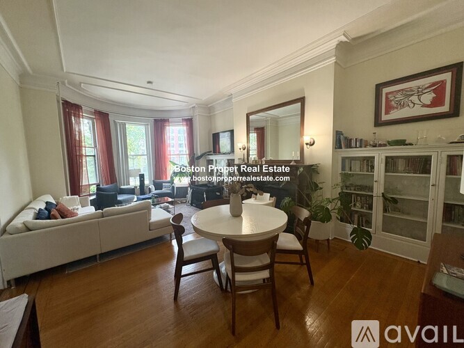 A living room with a white couch, a wooden table, and a television.