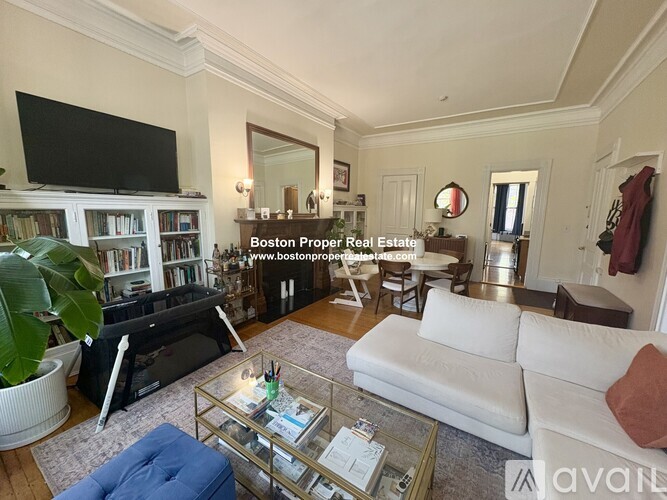 A living room with a white couch and a television on a stand.