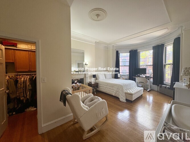 A bedroom with a bed, chair, and a window with curtains.