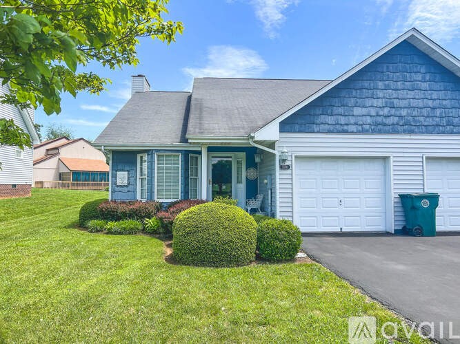 A blue house with a white garage door and a green trash can.