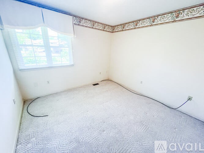 A room with a carpeted floor and a window with blinds.