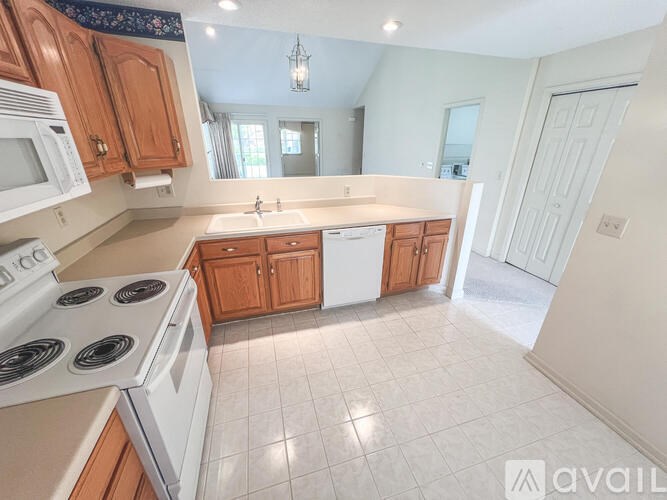 A kitchen with white appliances and wooden cabinets.