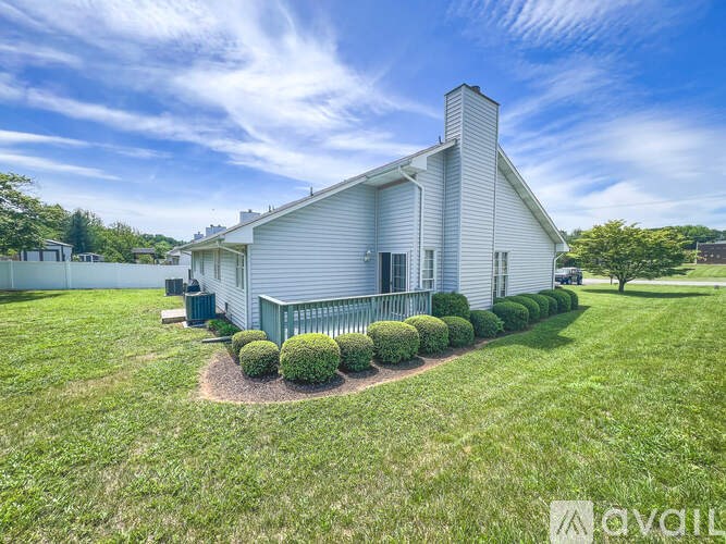 A white house with a green lawn and bushes in front.