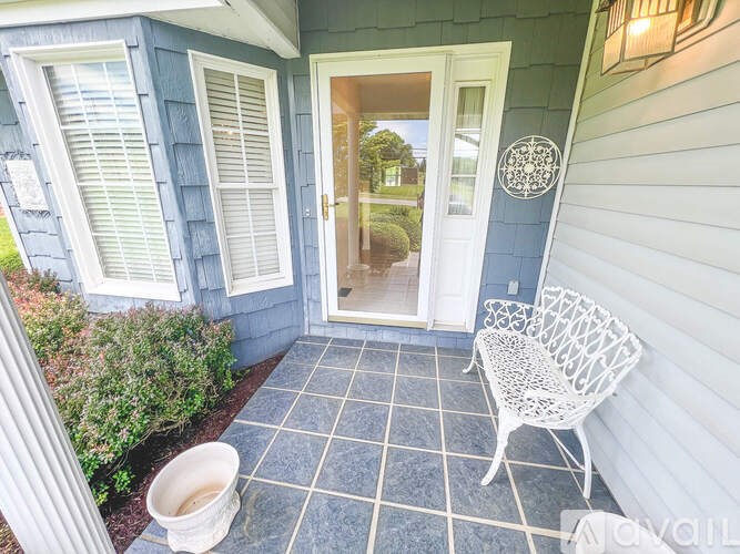 A white chair is on a porch with a blue wall.