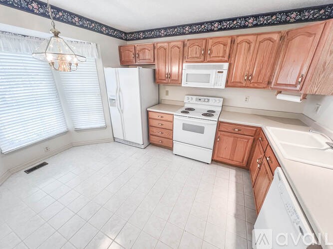 A kitchen with white appliances and brown cabinets.
