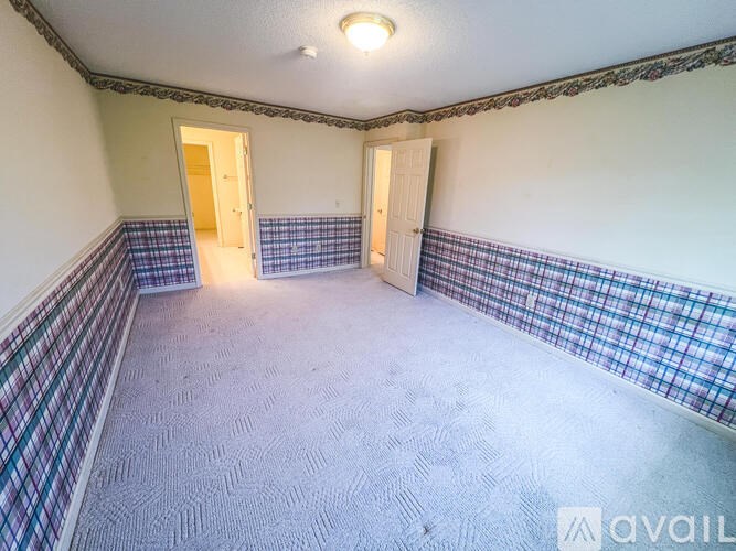 A room with a carpeted floor and two doors.