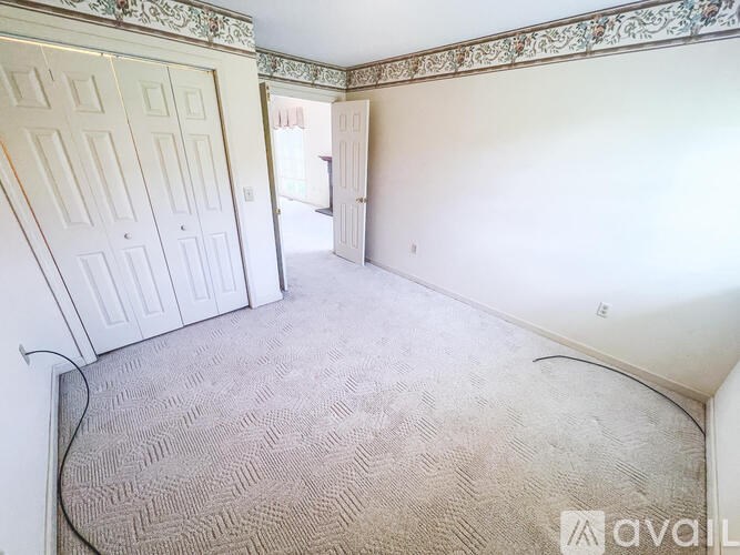 A carpeted room with a door and wallpapered walls.