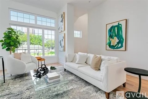 A living room with a white couch, a glass coffee table, and a painting on the wall.