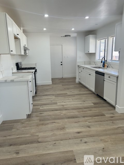 A kitchen with white cabinets and a wooden floor.