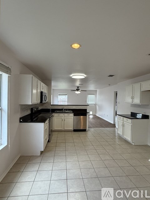 A kitchen with white cabinets and black countertops.
