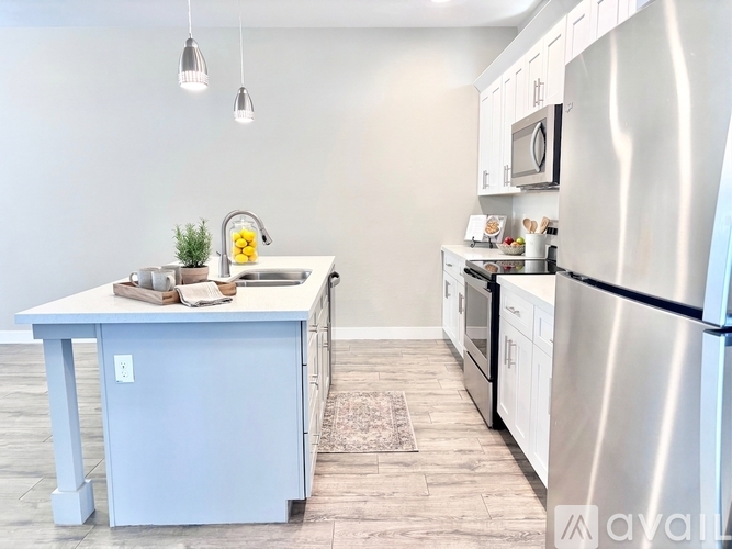 A kitchen with white cabinets and appliances, a white island, and a tiled floor.