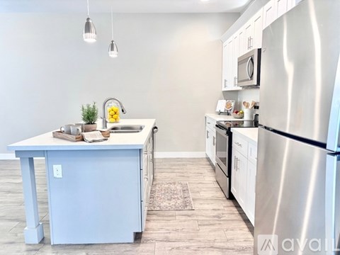 A kitchen with white cabinets and appliances, a white island, and a tiled floor.