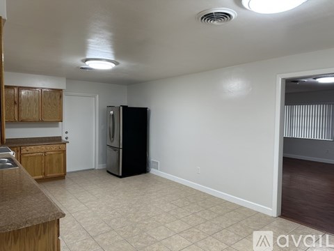 A kitchen with a black refrigerator and wooden cabinets.