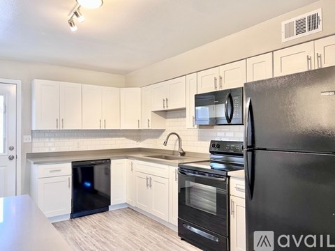A kitchen with white cabinets and black appliances.
