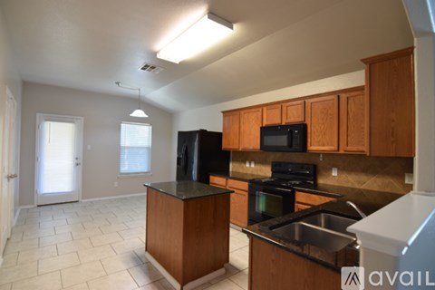 A kitchen with wooden cabinets and a black countertop.