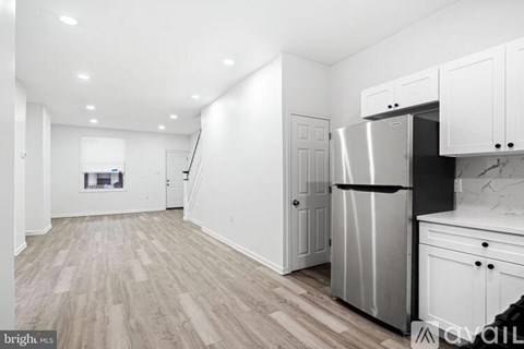 A kitchen with white cabinets and a stainless steel refrigerator.