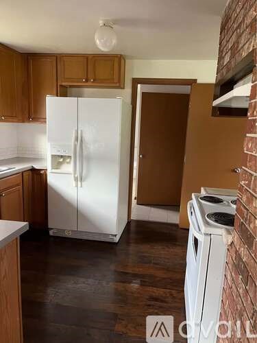 A white refrigerator is in a kitchen with wooden cabinets.