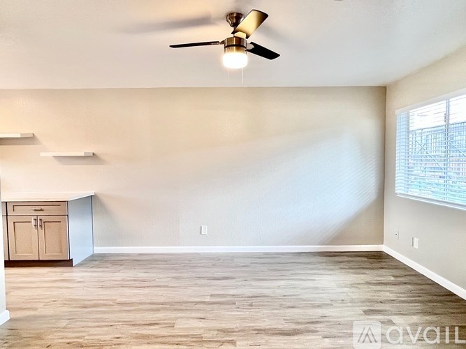 A room with a ceiling fan and wooden flooring.
