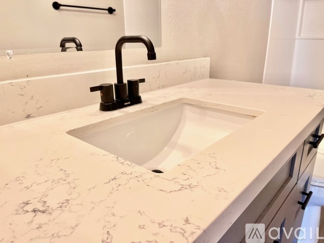 A white marble sink in a bathroom with a black faucet.