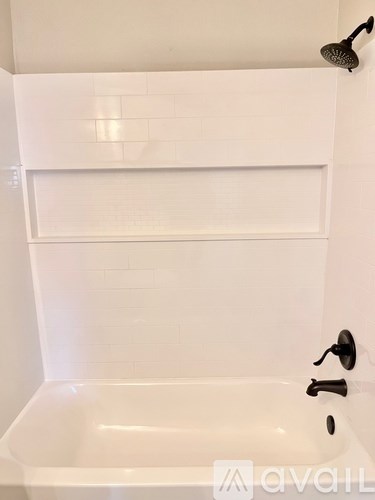 A white bathroom with a white tub and a black shower head.