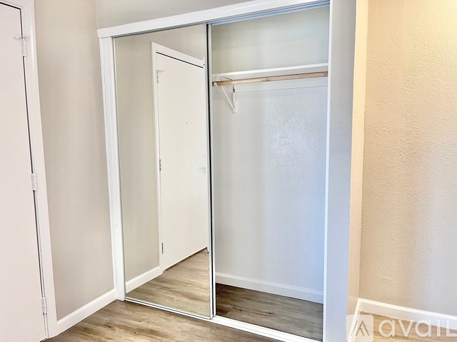 A white closet with a mirror door is open.