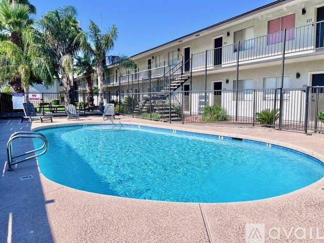 A swimming pool in front of a building with a balcony.