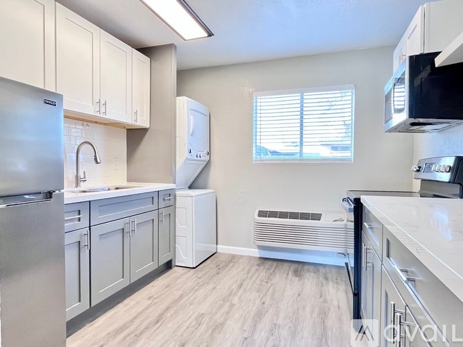 A kitchen with white cabinets and a stainless steel refrigerator.