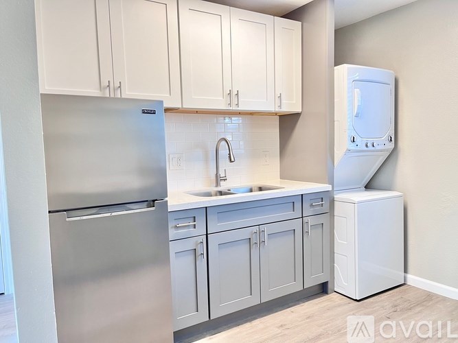 A kitchen with white cabinets and a stainless steel refrigerator.