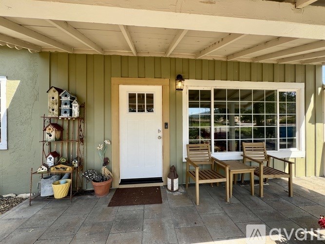A white door is on the left side of a patio with a table and chairs.