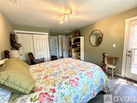 A bedroom with a floral bedspread and a mirror on the wall.
