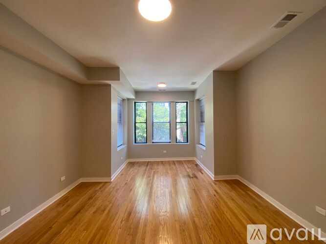 A spacious room with wooden flooring and a large window.