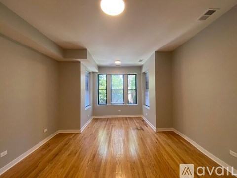 A spacious room with wooden flooring and a large window.