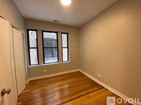 A room with wooden floors and a window overlooking a brick building.