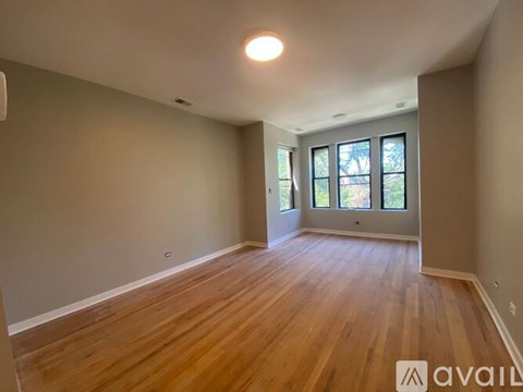 A room with wooden flooring and a window with a view of trees.