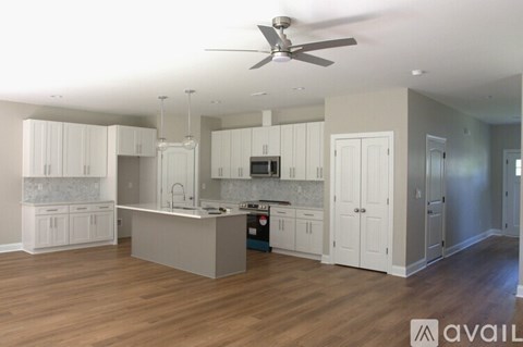 A spacious kitchen with white cabinets and a wooden floor.