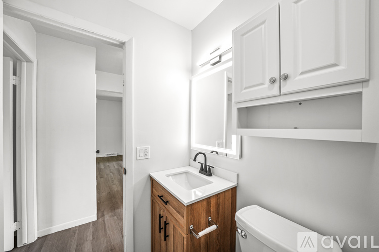 A white bathroom with a wooden vanity and a white bathtub.