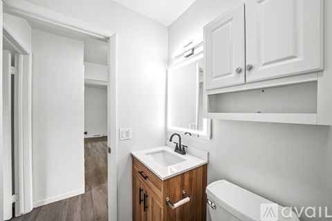A white bathroom with a wooden vanity and a white bathtub.