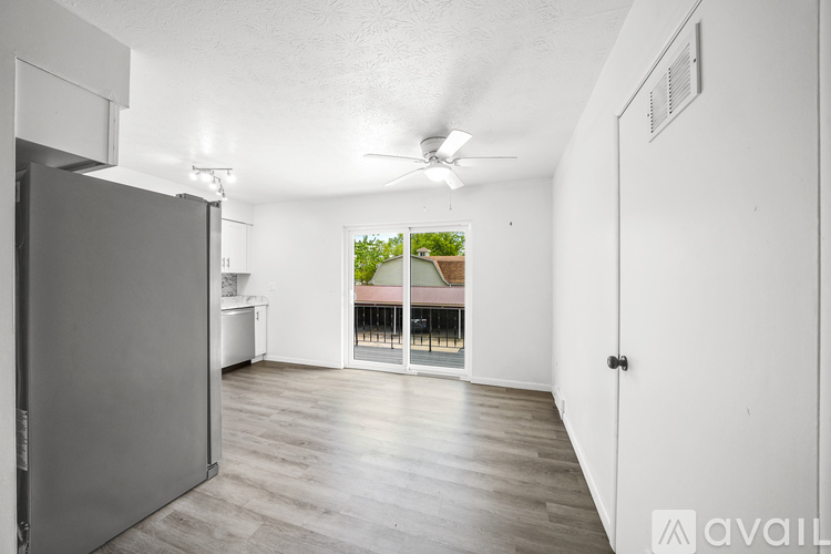 A spacious room with a ceiling fan and sliding glass doors leading to a balcony.
