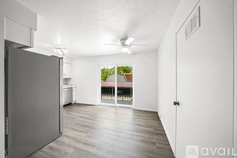 A spacious room with a ceiling fan and sliding glass doors leading to a balcony.