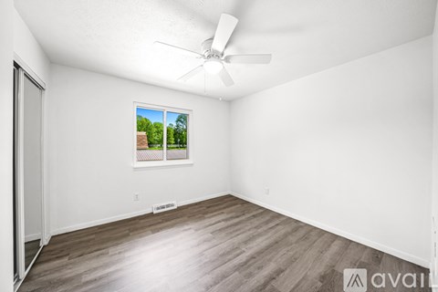 A room with a ceiling fan and a window showing a view of trees.