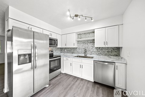 A kitchen with a refrigerator, microwave, oven, sink and cabinets.