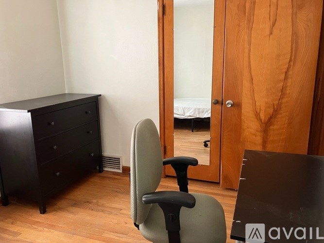 A room with a black dresser, a grey chair and a wooden door.