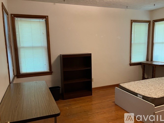 A room with a bed, a desk, and a bookshelf.