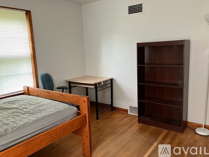 A bedroom with a bed, desk, and shelves.