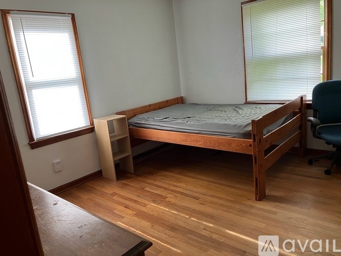A bedroom with a bed, chair, and window.