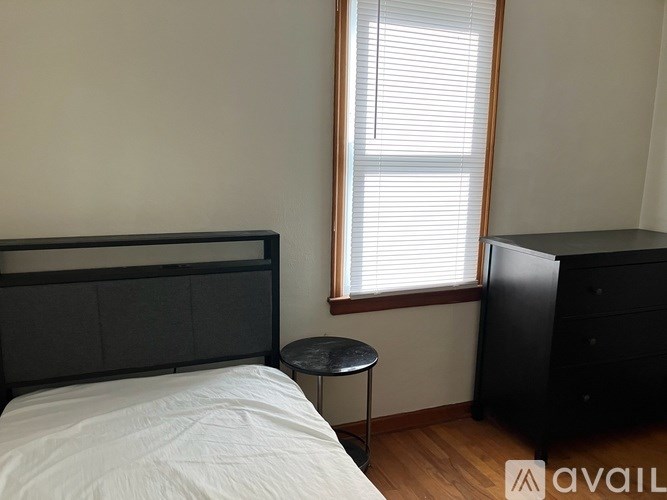A bedroom with a bed, a small table, and a window with blinds.